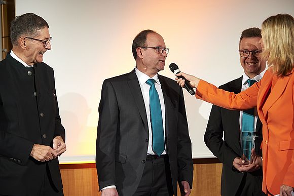 Preisträger Föckersperger mit Laudator und Moderatorin